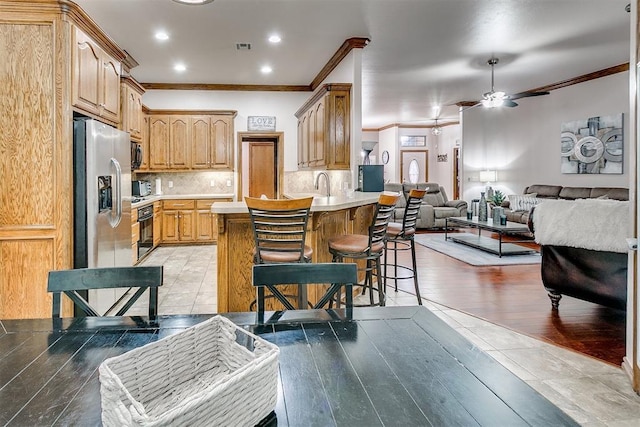 5608 Bent Creek Dr, Oklahoma City, OK 73135 - kitchen featuring ornamental molding, stainless steel refrigerator with ice dispenser, a peninsula, open floor plan, and light countertops