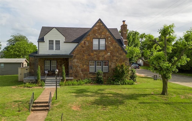 2650 NW 25th St, Oklahoma City, OK 73107 - tudor house featuring covered porch, a chimney, stone siding, and a front lawn