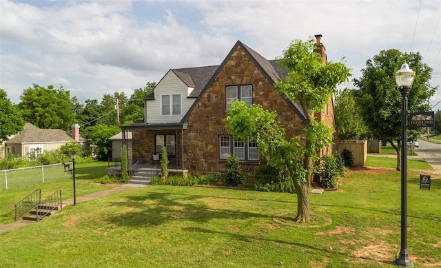 2650 NW 25th St, Oklahoma City, OK 73107 - tudor home with stone siding, a chimney, and a porch