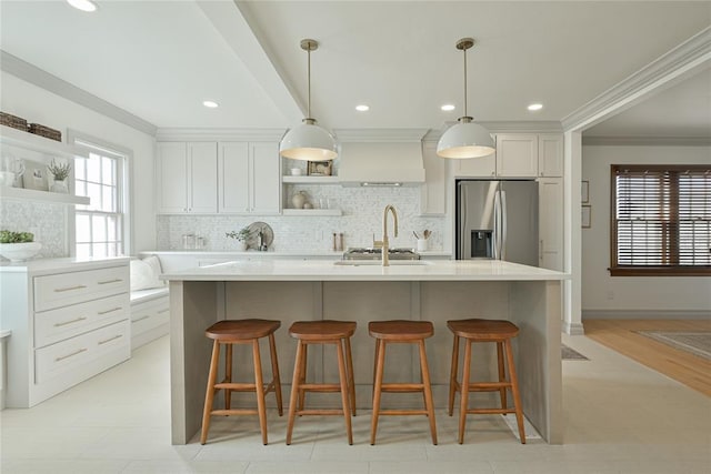 2650 NW 25th St, Oklahoma City, OK 73107 - kitchen with stainless steel fridge with ice dispenser, open shelves, premium range hood, a breakfast bar area, and decorative backsplash