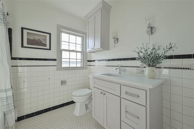 2650 NW 25th St, Oklahoma City, OK 73107 - bathroom featuring tile walls, toilet, vanity, tile patterned flooring, and a wainscoted wall