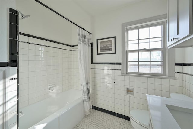 2650 NW 25th St, Oklahoma City, OK 73107 - bathroom featuring shower / bathtub combination with curtain, toilet, tile walls, tile patterned flooring, and wainscoting