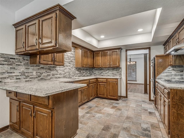 4400 Windsong Way, Oklahoma City, OK 73120 - kitchen with a peninsula, stainless steel appliances, decorative backsplash, a tray ceiling, and light stone finish floors