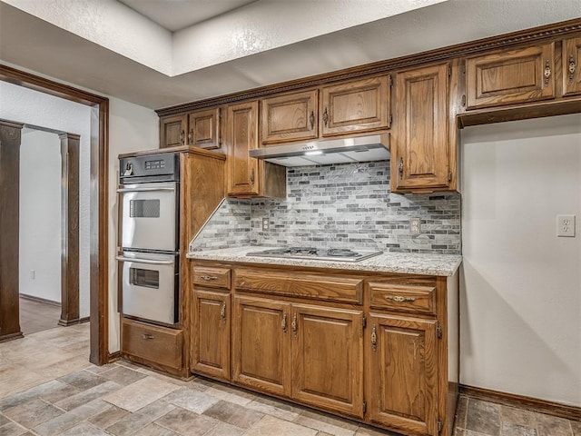 4400 Windsong Way, Oklahoma City, OK 73120 - kitchen with appliances with stainless steel finishes, under cabinet range hood, tasteful backsplash, baseboards, and brown cabinetry