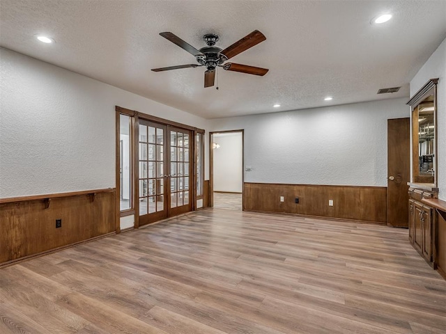 4400 Windsong Way, Oklahoma City, OK 73120 - empty room with french doors, light wood-style floors, wooden walls, a wainscoted wall, and ceiling fan