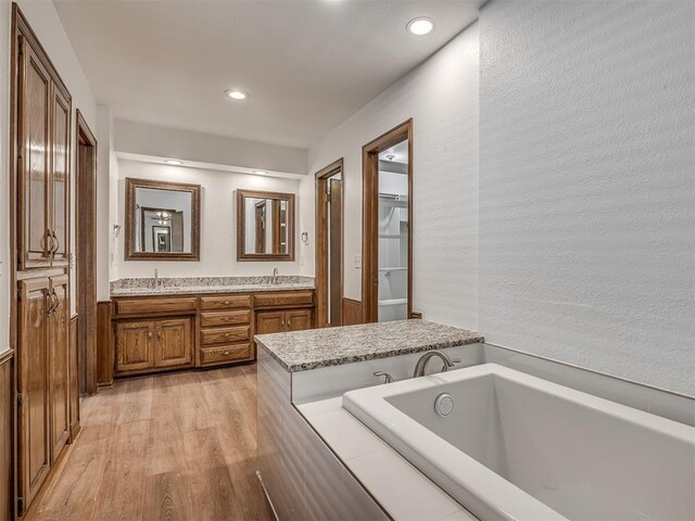 4400 Windsong Way, Oklahoma City, OK 73120 - full bath featuring double vanity, a garden tub, wood finished floors, recessed lighting, and a textured wall