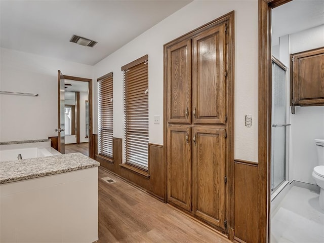 4400 Windsong Way, Oklahoma City, OK 73120 - bathroom featuring toilet, wainscoting, a stall shower, a garden tub, and wood finished floors