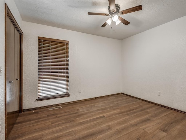 4400 Windsong Way, Oklahoma City, OK 73120 - spare room featuring wood finished floors, a ceiling fan, baseboards, a textured wall, and a textured ceiling