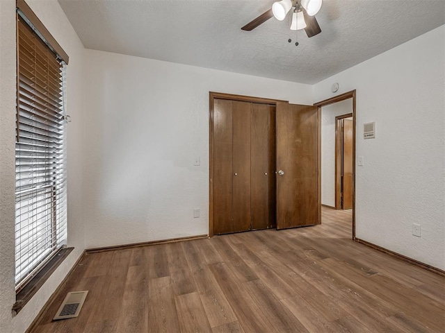 4400 Windsong Way, Oklahoma City, OK 73120 - unfurnished bedroom featuring wood finished floors, a closet, baseboards, ceiling fan, and a textured wall