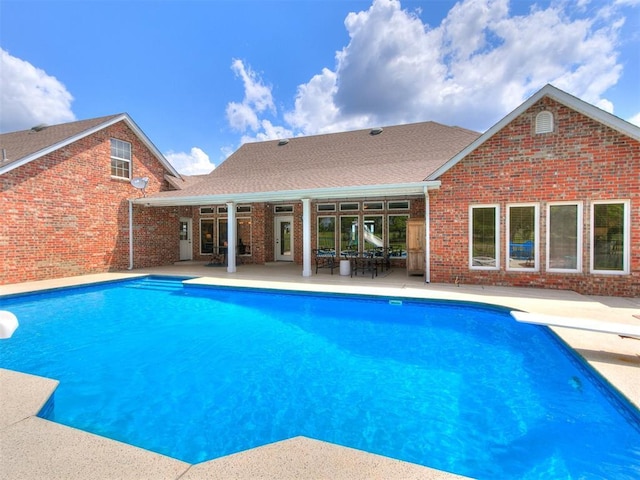 outdoor pool featuring a patio area and a diving board