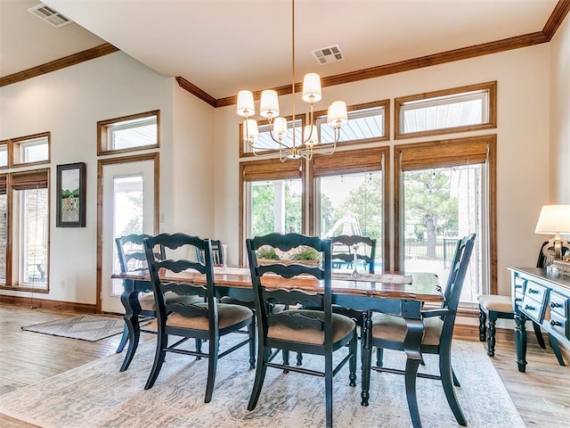 dining space with light wood-style flooring, crown molding, a chandelier, and baseboards
