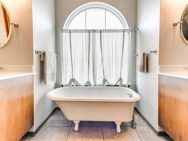 bathroom featuring a freestanding bath, tile patterned floors, and baseboards