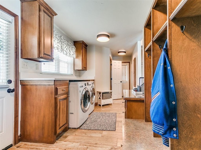 clothes washing area with washing machine and clothes dryer, cabinet space, and light wood-type flooring