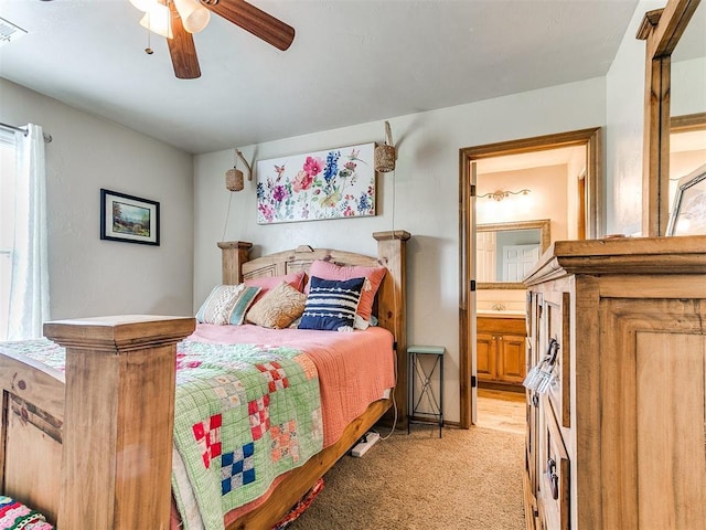bedroom with light colored carpet, ensuite bath, and a ceiling fan