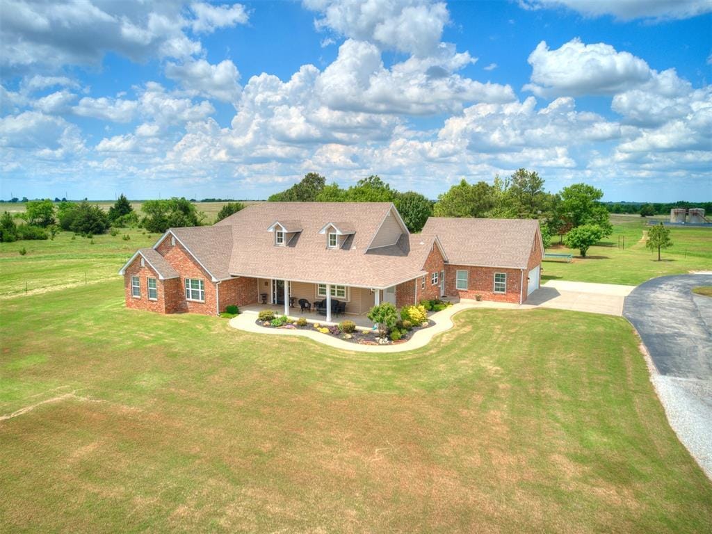 1486 County St Unit 2910 20, Acres Tuttle, OK 73089 - cape cod-style house featuring brick siding, asphalt driveway, a front lawn, and a porch