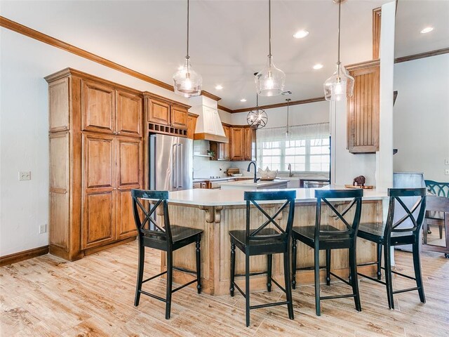 1486 County St Unit 2910 20, Acres Tuttle, OK 73089 - kitchen with high end fridge, premium range hood, brown cabinetry, ornamental molding, and light countertops