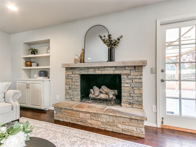 6709 Reed Dr, Oklahoma City, OK 73116 - living area with dark wood-style floors, a stone fireplace, built in shelves, and baseboards