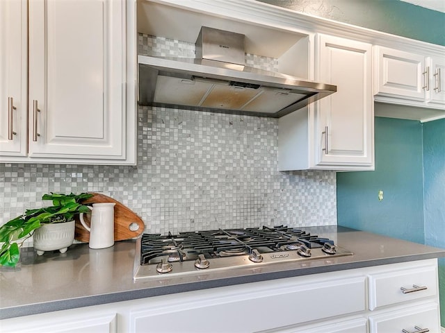 6709 Reed Dr, Oklahoma City, OK 73116 - kitchen featuring stainless steel gas stovetop, wall chimney range hood, tasteful backsplash, and white cabinetry