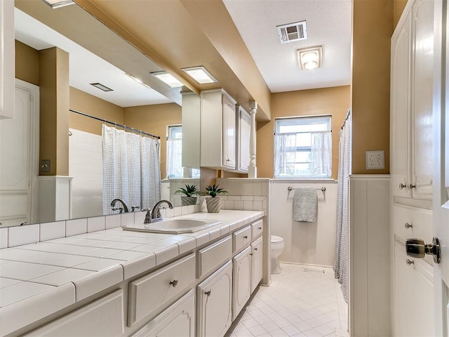 6709 Reed Dr, Oklahoma City, OK 73116 - full bathroom with toilet, wainscoting, tile patterned flooring, vanity, and a shower with shower curtain
