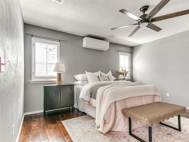 6709 Reed Dr, Oklahoma City, OK 73116 - bedroom with a wall unit AC, wood-type flooring, a textured ceiling, baseboards, and a ceiling fan