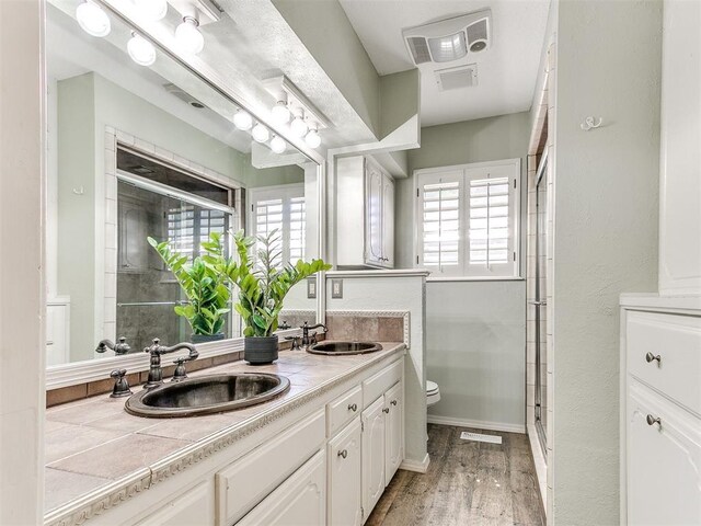 6709 Reed Dr, Oklahoma City, OK 73116 - bathroom with toilet, a shower stall, wood finished floors, and double vanity