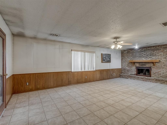 2915 N W Oaks Pl, Newcastle, OK 73065 - unfurnished living room with a wainscoted wall, wood walls, a ceiling fan, a brick fireplace, and a textured ceiling