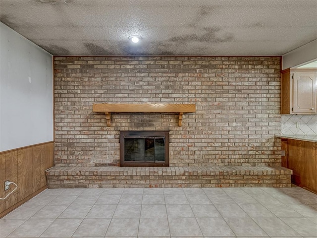 2915 N W Oaks Pl, Newcastle, OK 73065 - unfurnished living room with a brick fireplace, wainscoting, a textured ceiling, and wooden walls