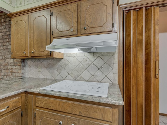 2915 N W Oaks Pl, Newcastle, OK 73065 - kitchen featuring under cabinet range hood, white electric stovetop, backsplash, and brown cabinetry