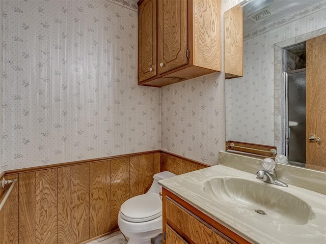 2915 N W Oaks Pl, Newcastle, OK 73065 - bathroom featuring wallpapered walls, toilet, vanity, wainscoting, and a shower with door