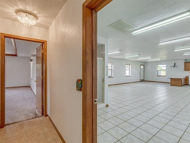 2915 N W Oaks Pl, Newcastle, OK 73065 - corridor with light tile patterned flooring, a textured ceiling, a textured wall, baseboards, and a chandelier