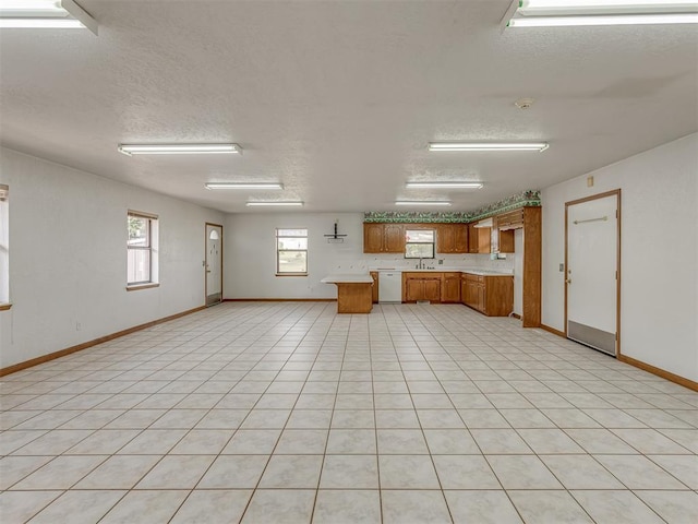 2915 N W Oaks Pl, Newcastle, OK 73065 - kitchen with white dishwasher, brown cabinets, light countertops, a textured ceiling, and baseboards