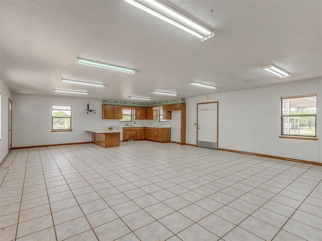 2915 N W Oaks Pl, Newcastle, OK 73065 - kitchen with open floor plan, brown cabinetry, light countertops, baseboards, and a textured ceiling