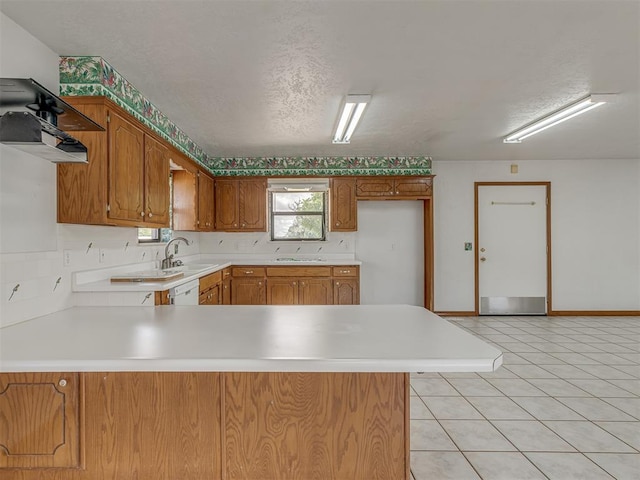 2915 N W Oaks Pl, Newcastle, OK 73065 - kitchen with a peninsula, light countertops, brown cabinets, a sink, and light tile patterned floors