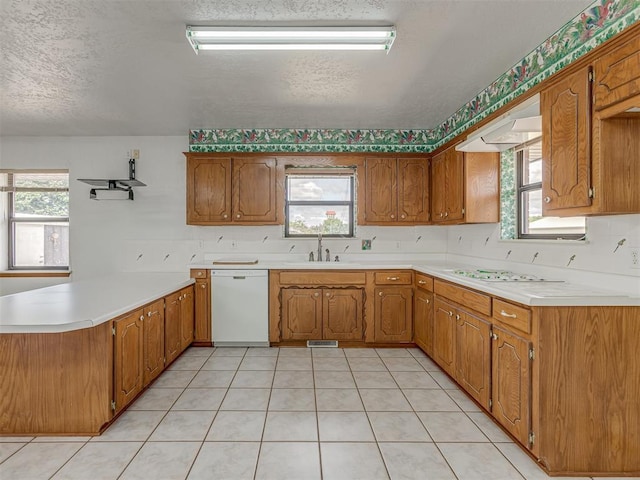 2915 N W Oaks Pl, Newcastle, OK 73065 - kitchen with white appliances, a peninsula, a sink, a textured ceiling, and brown cabinets