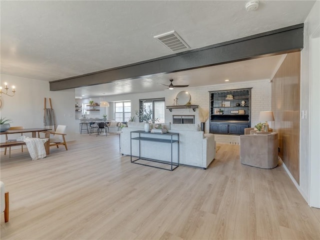 5613 NW 115th St, Oklahoma City, OK 73162 - living room featuring light wood-style floors, a brick fireplace, a chandelier, and a ceiling fan