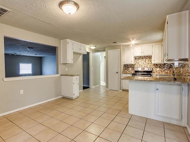 kitchen with stainless steel electric range, a sink, light tile patterned floors, backsplash, and a peninsula
