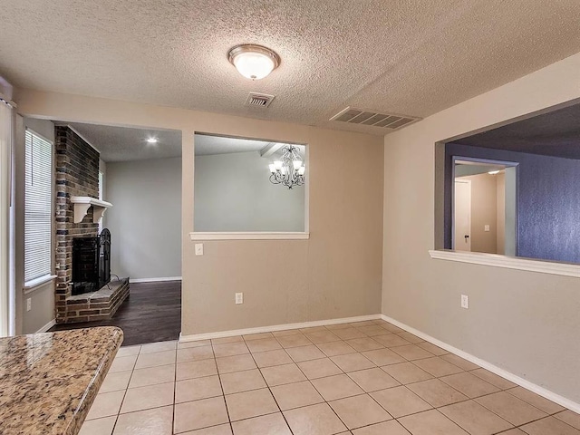 unfurnished living room featuring a textured ceiling, a fireplace, light tile patterned flooring, and baseboards