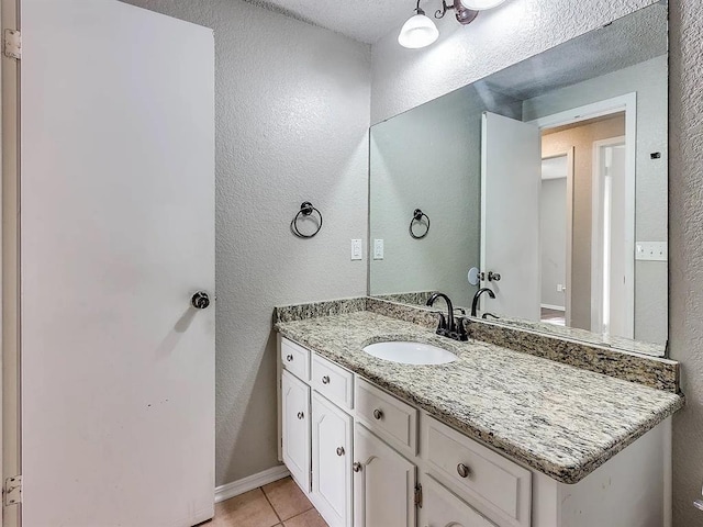bathroom featuring tile patterned floors, vanity, and a textured wall
