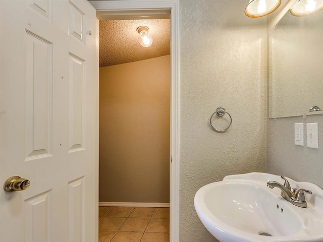 bathroom featuring a sink, tile patterned floors, a textured ceiling, and baseboards
