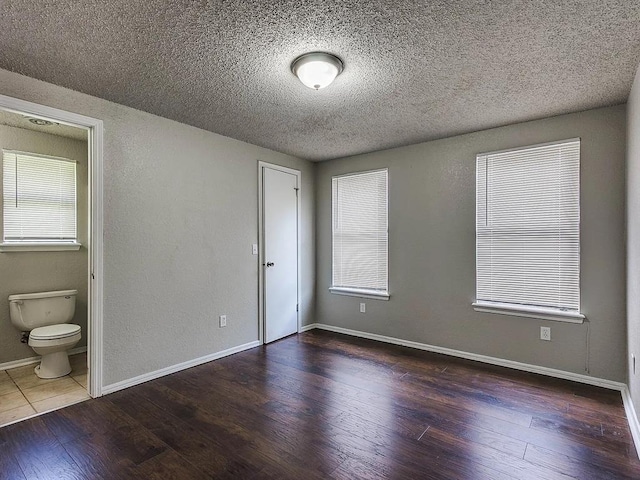 empty room featuring wood finished floors, a textured ceiling, and baseboards
