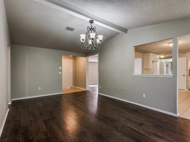 spare room featuring wood finished floors, a textured ceiling, a chandelier, and baseboards