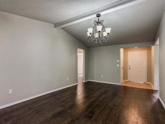 unfurnished room with wood finished floors, a chandelier, a textured ceiling, and baseboards