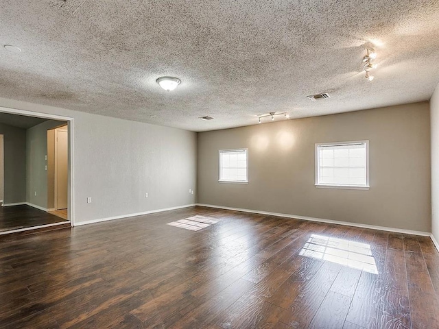 unfurnished room featuring rail lighting, baseboards, dark wood-style flooring, and a textured ceiling