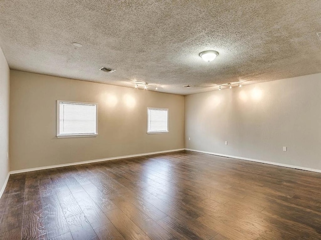 unfurnished room with rail lighting, dark wood finished floors, baseboards, and a textured ceiling