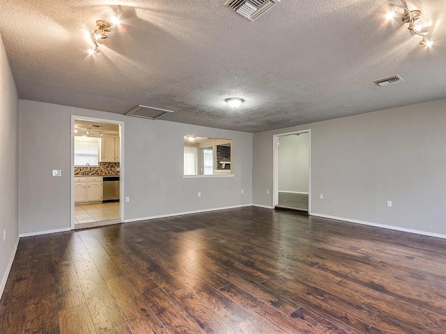 spare room featuring a textured ceiling, wood-type flooring, track lighting, a sink, and baseboards