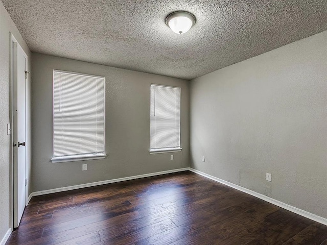 unfurnished room with wood finished floors, a textured ceiling, and baseboards
