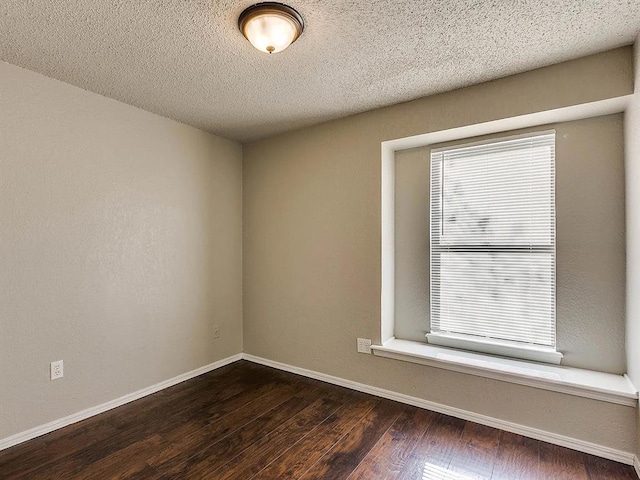 empty room featuring wood-type flooring, baseboards, and a textured ceiling