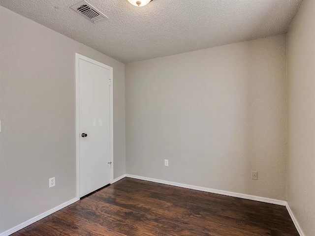 empty room featuring dark wood-type flooring, baseboards, and a textured ceiling