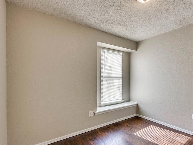 spare room featuring wood finished floors, baseboards, and a textured ceiling
