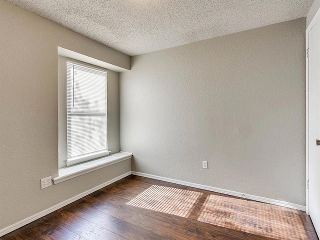 spare room featuring baseboards, wood finished floors, a textured ceiling, and a textured wall